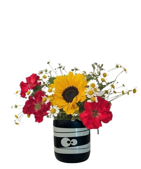 carnations, chamomile, and sunflowers in a halloween themed jar