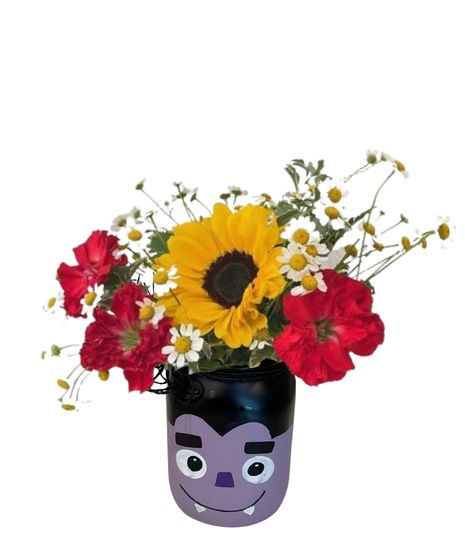 carnations, chamomile, and sunflowers in a halloween themed jar