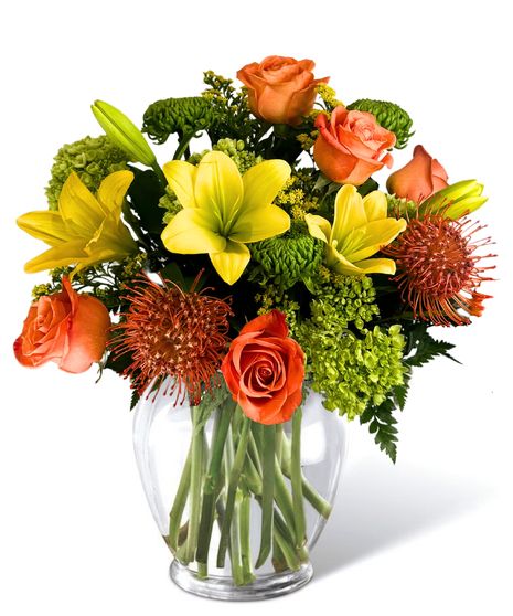  Roses, hydrangea, lilies, and pin cushion protea in a clear glass vase..