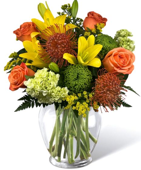  Roses, hydrangea, lilies, and pin cushion protea in a clear glass vase..